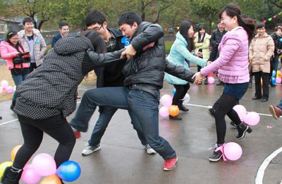 男女青年在進(jìn)行愛的路上你追我趕踩氣球趣味競(jìng)賽活動(dòng)。