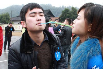 男女青年在進(jìn)行吸管運(yùn)輸趣味競(jìng)賽活動(dòng)。
